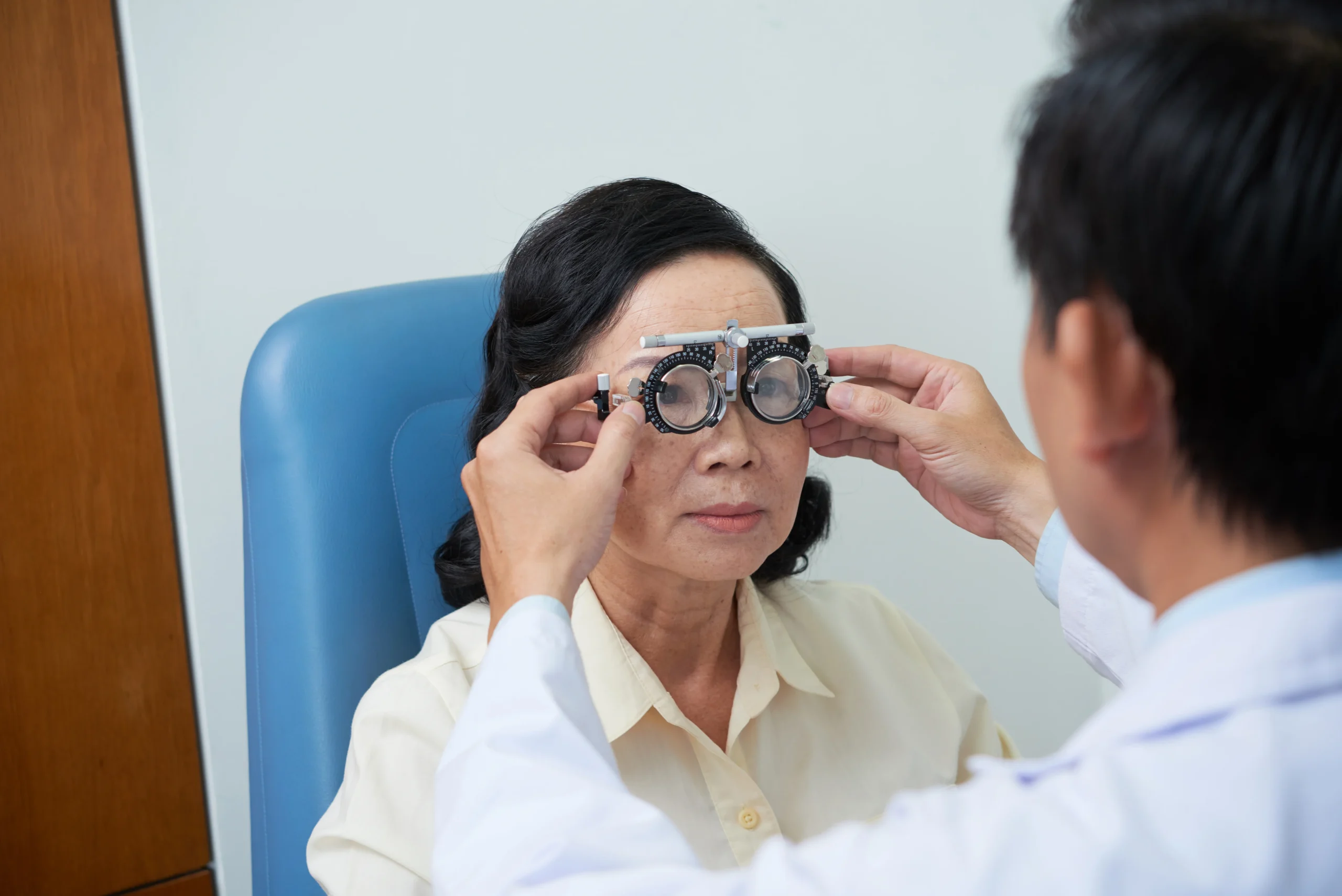 unrecognizable-male-ophtalmologist-fitting-trial-lens-frame-senior-female-patient